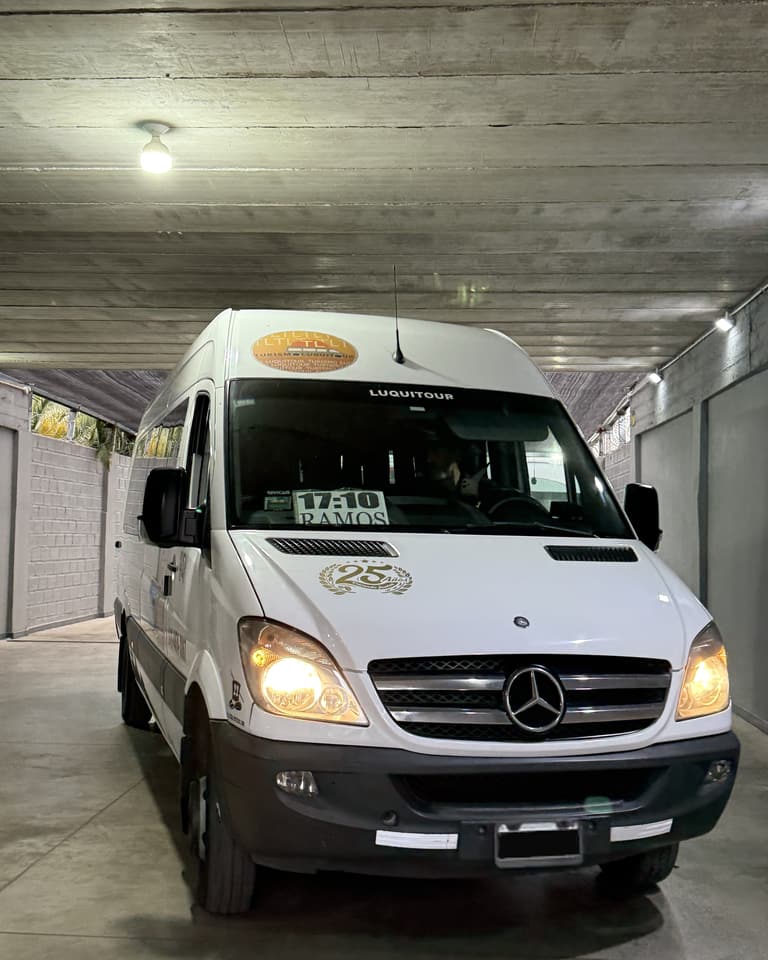 Combi de Luquitour de frente, con las luces encendidas, en la cochera de la empresa