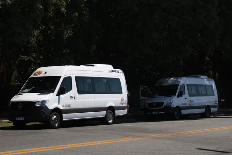 Dos combis Mercedes-Benz Sprinter de Luquitour estacionadas bajo los árboles