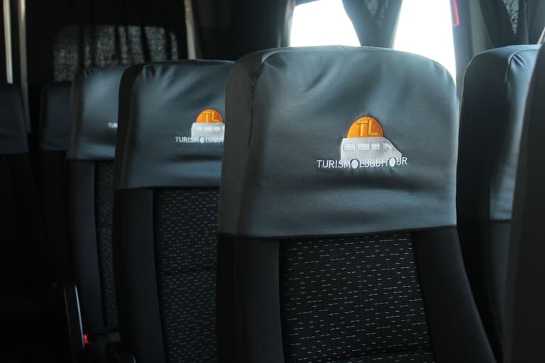Asientos de una combi de Luquitour con el logo de la empresa bordado en las cabeceras
